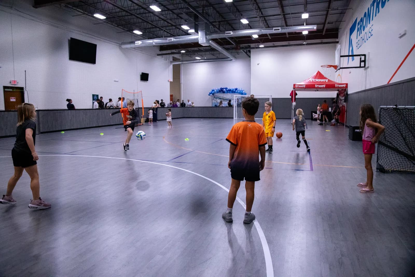 Campers sprinting through a speed and agility ladder on the indoor courts at Frontrunner Fieldhouse